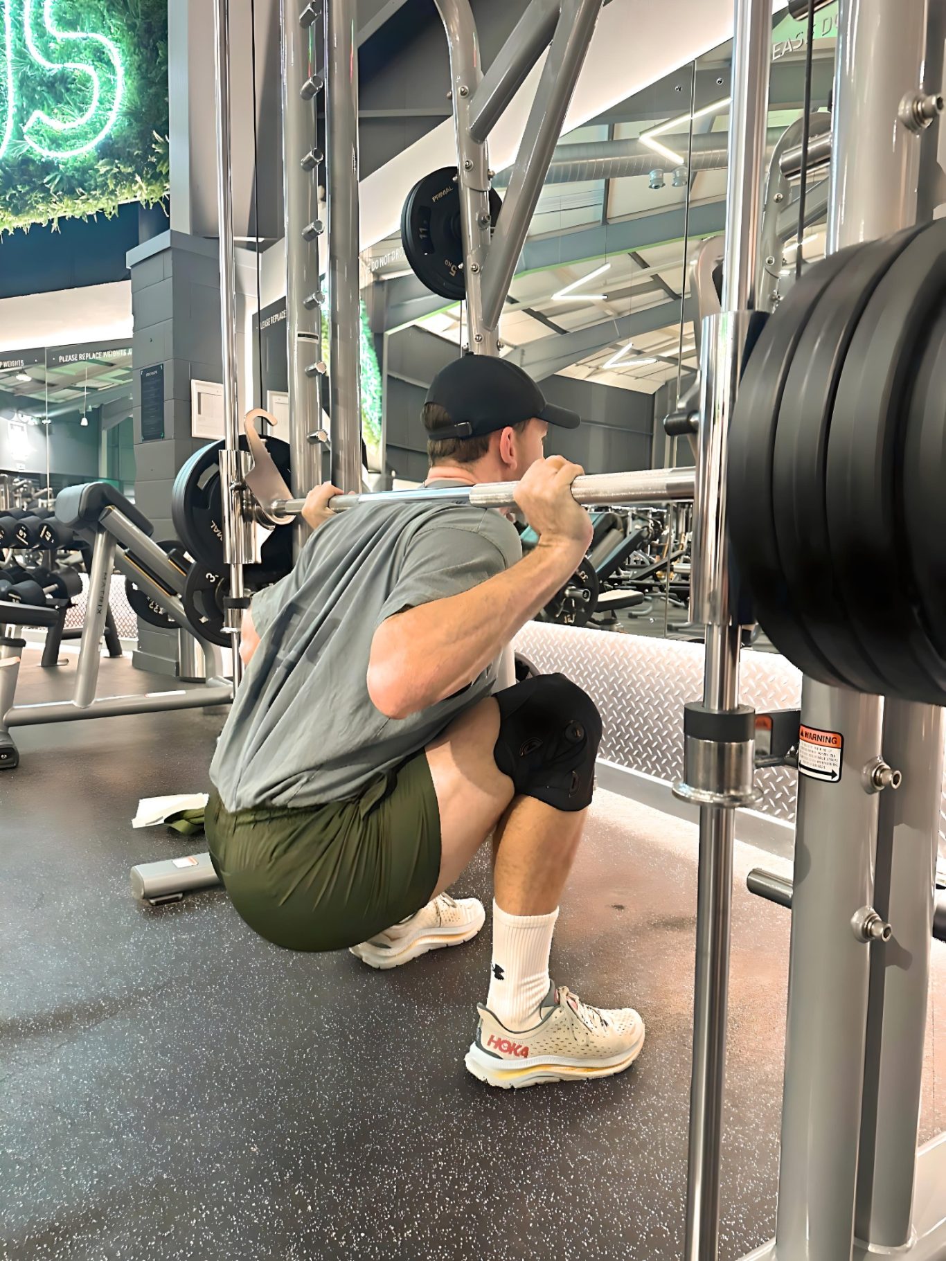 A person performing a squat with a barbell in a gym environment.